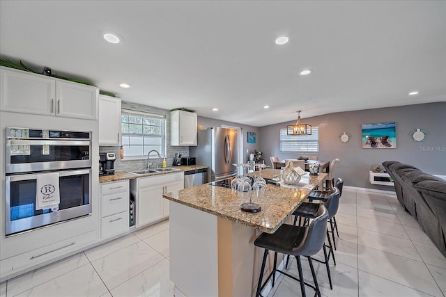 kitchen featuring appliances with stainless steel finishes, a center island, white cabinetry, and sink