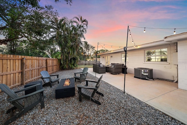 patio terrace at dusk featuring central AC unit and an outdoor living space with a fire pit