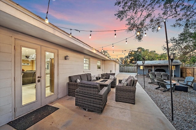 patio terrace at dusk with french doors and an outdoor living space with a fire pit