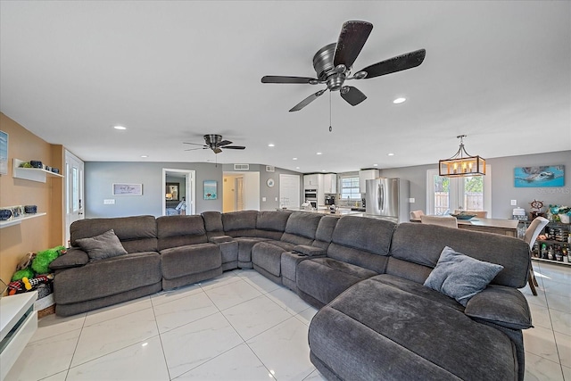 tiled living room with ceiling fan with notable chandelier