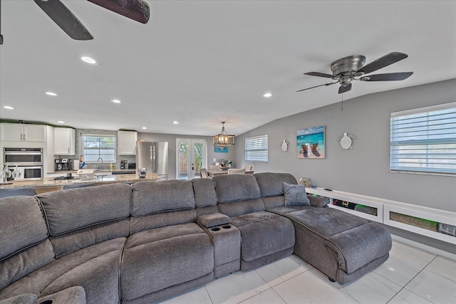 tiled living room featuring sink, ceiling fan with notable chandelier, a healthy amount of sunlight, and vaulted ceiling