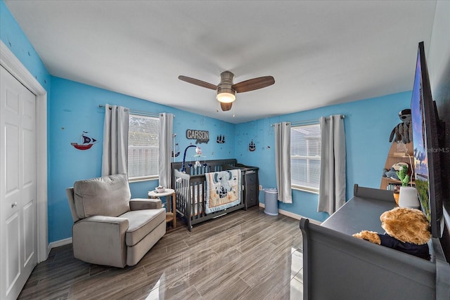 bedroom featuring hardwood / wood-style floors, ceiling fan, a crib, and a closet