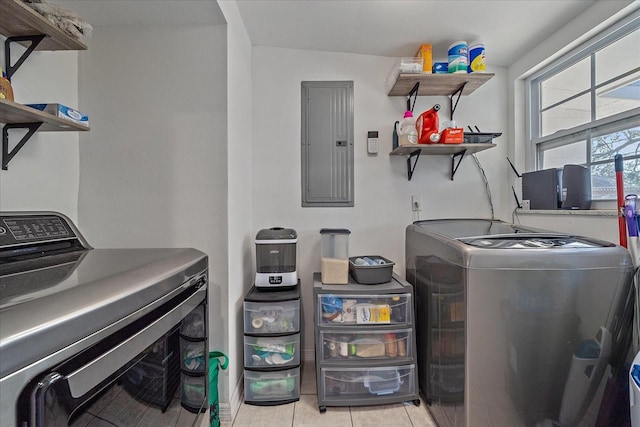 clothes washing area featuring washer and dryer, light tile patterned floors, and electric panel