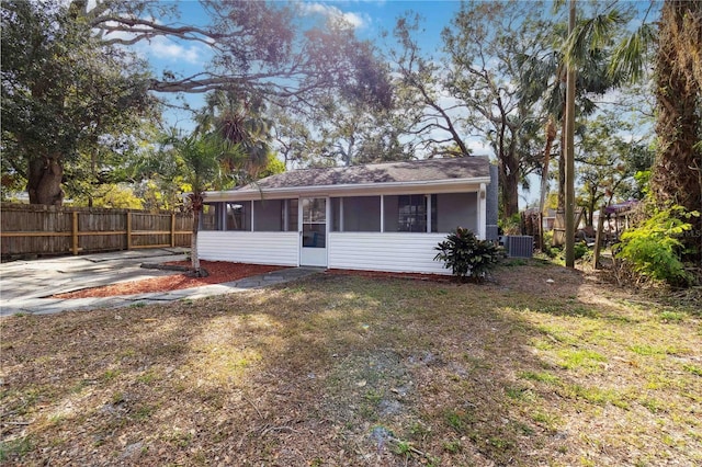 view of front facade with cooling unit, a sunroom, and a front yard