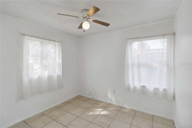 tiled empty room with ceiling fan and a textured ceiling