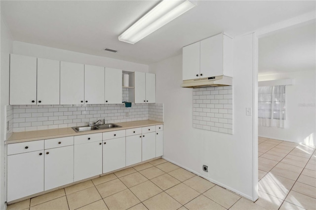 kitchen with light tile patterned floors, sink, decorative backsplash, and white cabinets