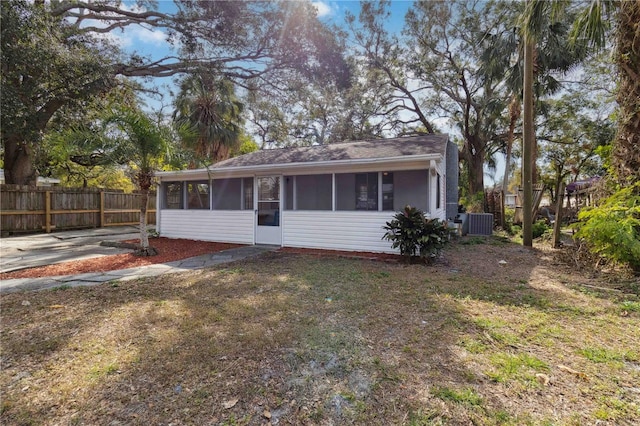 view of front of house featuring a sunroom, a front yard, and central air condition unit