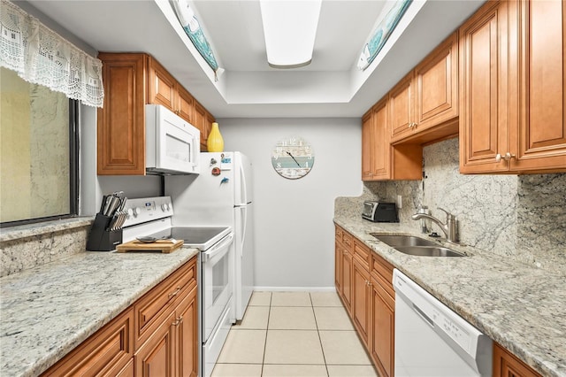 kitchen featuring white appliances, light stone countertops, decorative backsplash, light tile patterned flooring, and sink