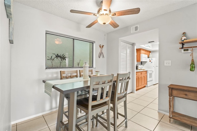 dining area featuring ceiling fan, a textured ceiling, and light tile patterned floors