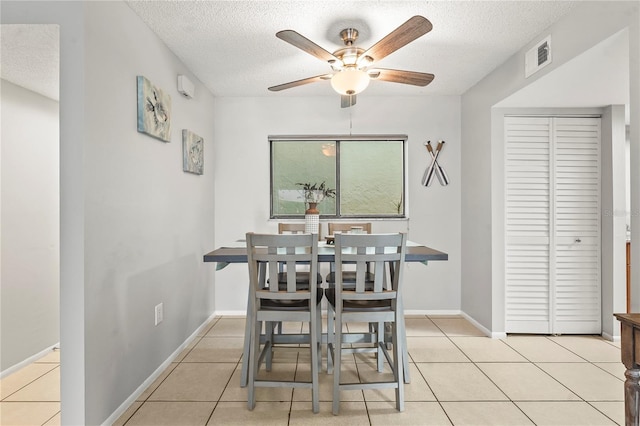 tiled dining room featuring a textured ceiling and ceiling fan