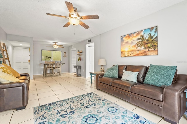 living room featuring light tile patterned floors, visible vents, ceiling fan, a textured ceiling, and baseboards