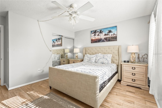 bedroom featuring baseboards, ceiling fan, light wood-style flooring, and a textured ceiling