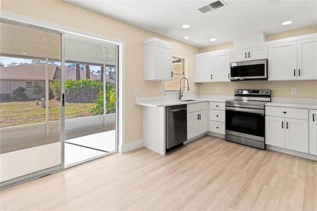 kitchen with white cabinets, appliances with stainless steel finishes, and a wealth of natural light