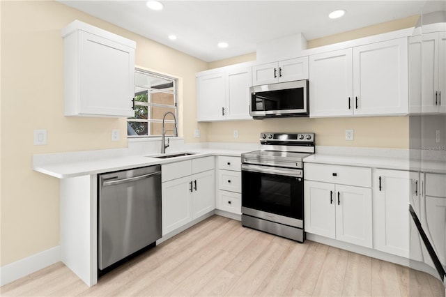 kitchen with white cabinetry, sink, light hardwood / wood-style flooring, and appliances with stainless steel finishes