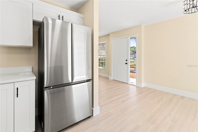 kitchen with stainless steel refrigerator, white cabinets, and light wood-type flooring