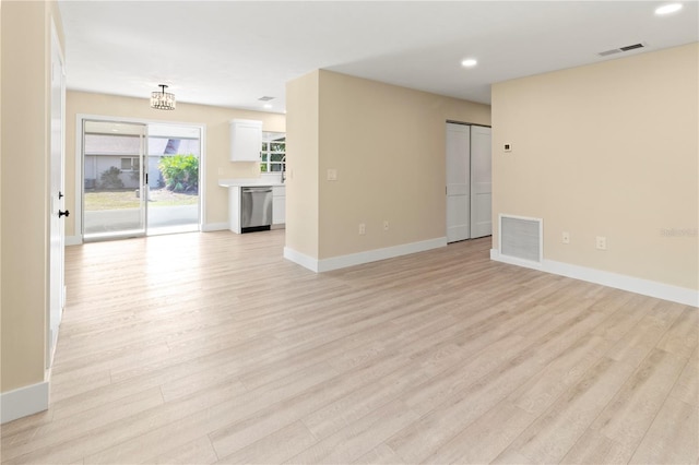 unfurnished living room with light hardwood / wood-style flooring and a notable chandelier