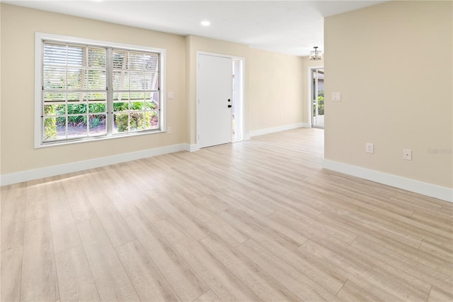 empty room featuring a notable chandelier and light hardwood / wood-style floors