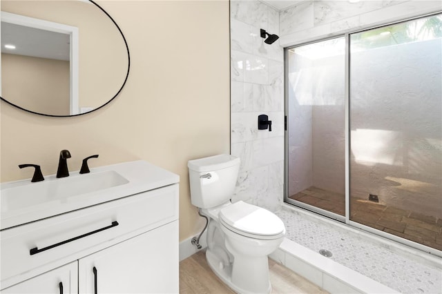 bathroom featuring toilet, vanity, wood-type flooring, and tiled shower