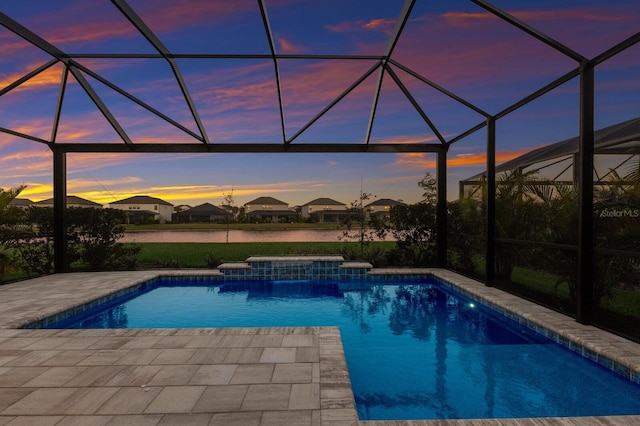 pool at dusk with a lanai, a hot tub, a patio, and a water view