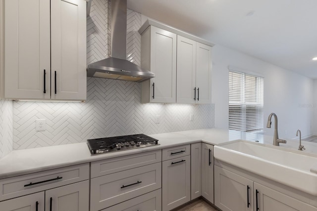 kitchen with tasteful backsplash, wall chimney exhaust hood, stainless steel gas stovetop, and sink