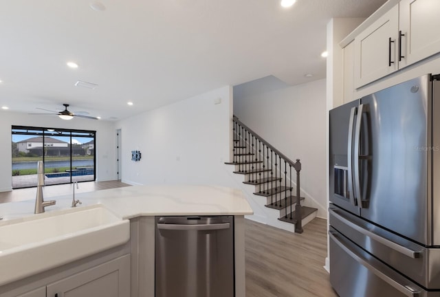 kitchen featuring sink, white cabinetry, appliances with stainless steel finishes, ceiling fan, and light hardwood / wood-style floors