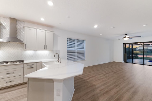 kitchen with white cabinetry, wall chimney exhaust hood, stainless steel gas stovetop, and sink