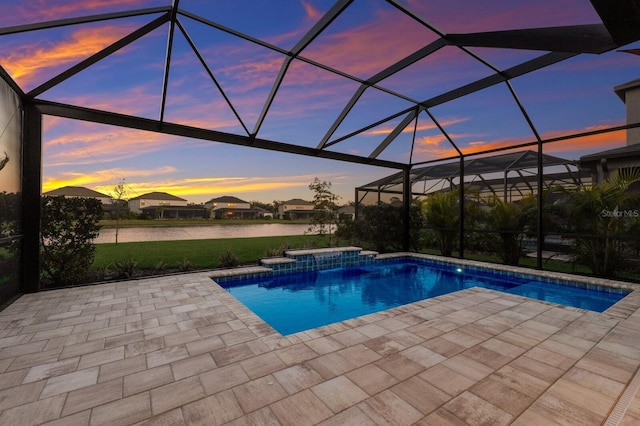 pool at dusk featuring a water view, a lanai, and a patio area