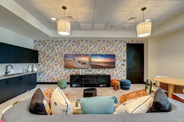 living room featuring a drop ceiling and sink