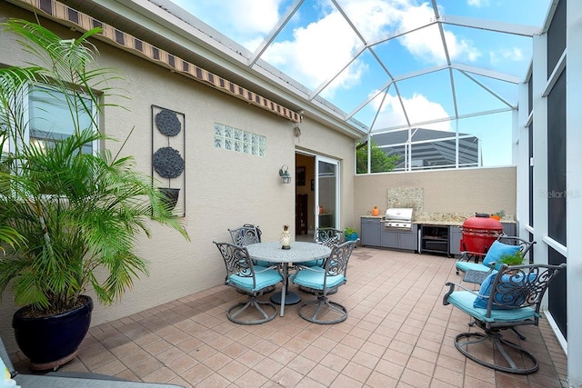 view of patio / terrace featuring glass enclosure, an outdoor kitchen, and area for grilling