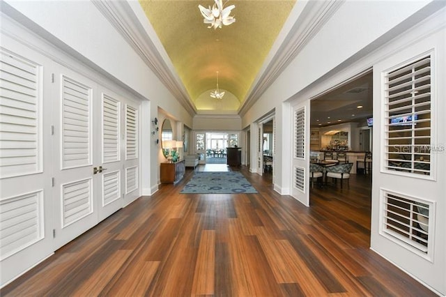 entryway featuring ornamental molding, a chandelier, vaulted ceiling, and dark hardwood / wood-style flooring