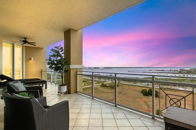 balcony at dusk featuring a water view