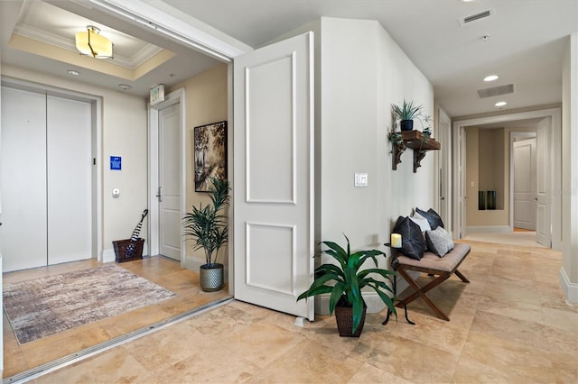 foyer entrance featuring a raised ceiling and ornamental molding