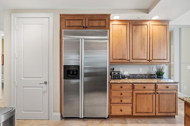 kitchen featuring built in refrigerator and dark stone counters