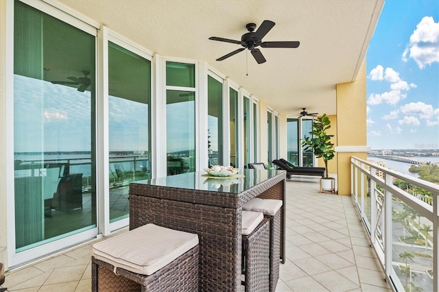 balcony featuring a water view and ceiling fan