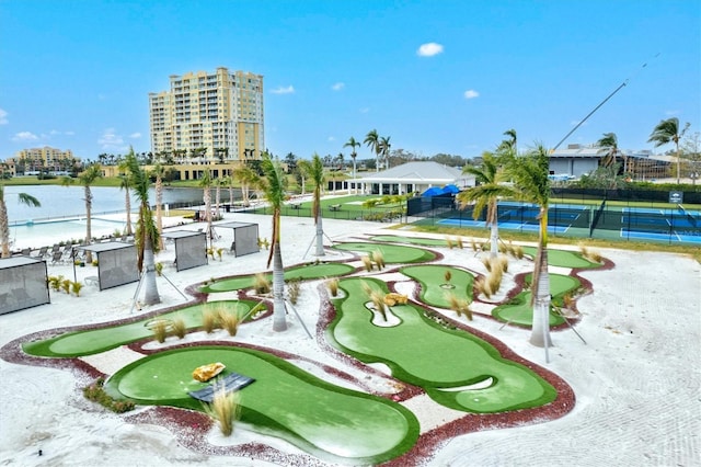 view of community featuring a tennis court, golf course view, a water view, and fence