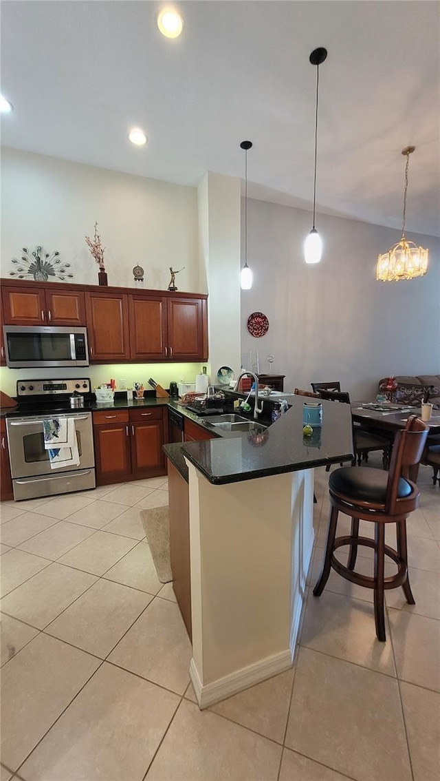 kitchen with hanging light fixtures, stainless steel appliances, light tile patterned floors, a kitchen breakfast bar, and sink