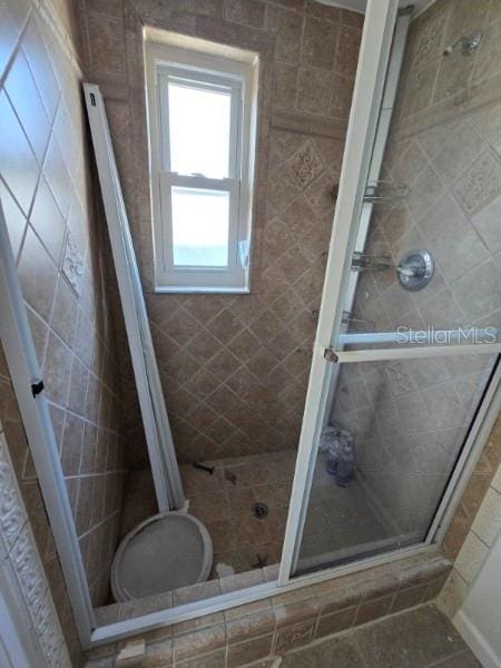 bathroom with a shower with shower door and tile patterned flooring