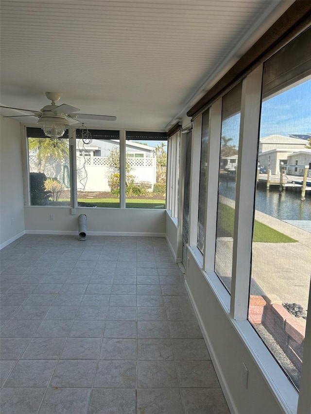 unfurnished sunroom with a water view and ceiling fan