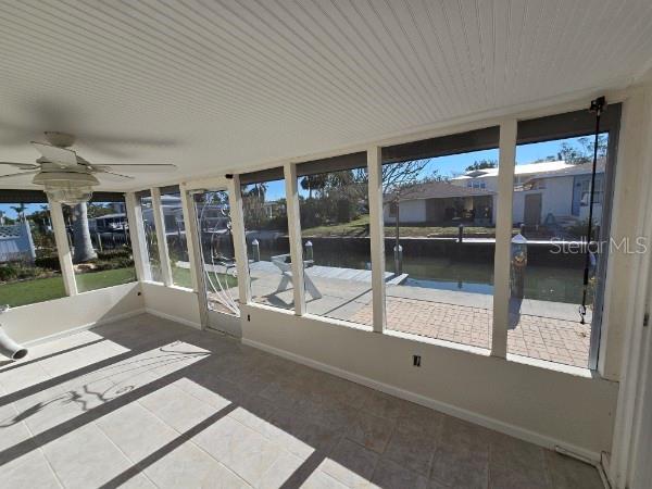 unfurnished sunroom featuring ceiling fan and a water view