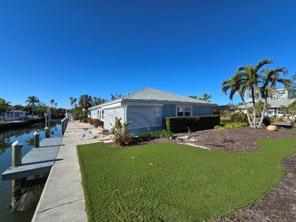 view of property exterior with a yard, a water view, and a boat dock