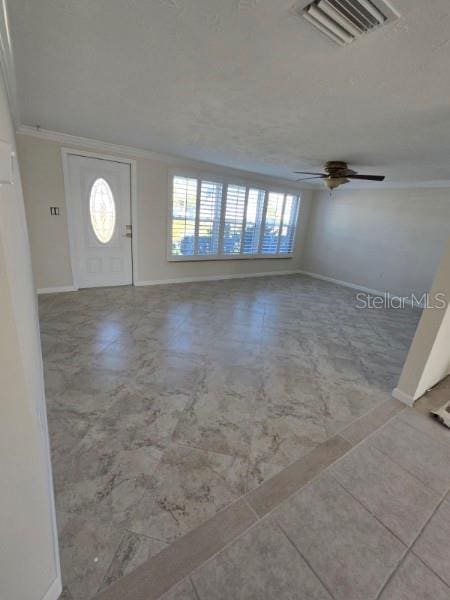foyer entrance with baseboards, tile patterned floors, crown molding, a ceiling fan, and visible vents
