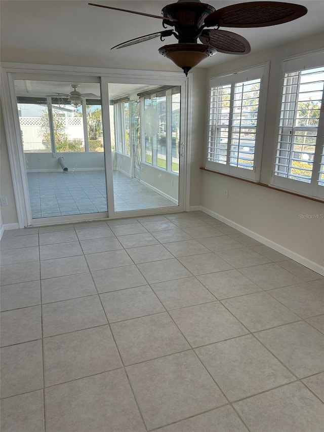 spare room with tile patterned floors, ceiling fan, and baseboards