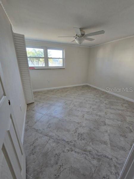 spare room with baseboards and a ceiling fan