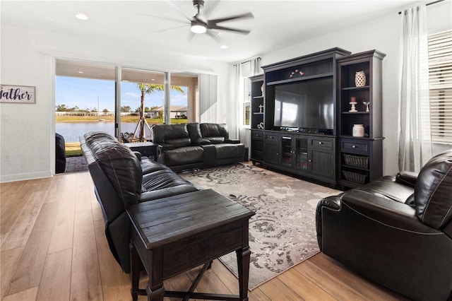 living room featuring light hardwood / wood-style floors, a water view, and ceiling fan