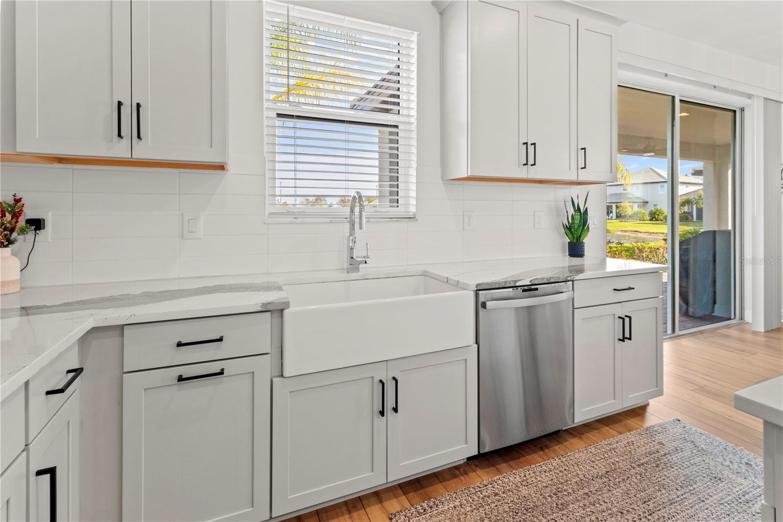 kitchen with tasteful backsplash, dishwasher, white cabinets, light hardwood / wood-style flooring, and light stone counters