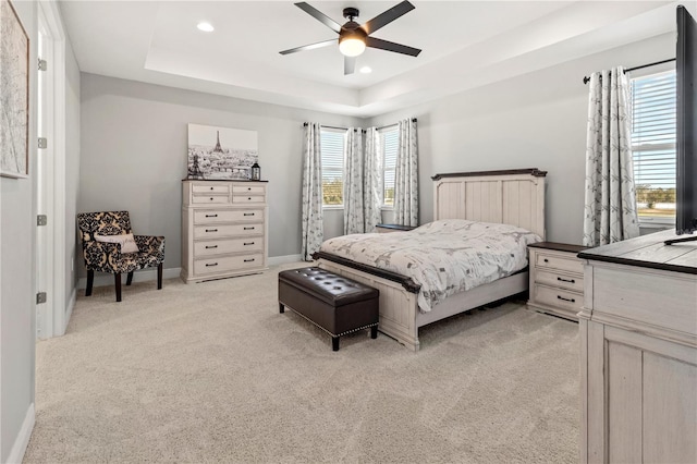 carpeted bedroom featuring ceiling fan and a tray ceiling