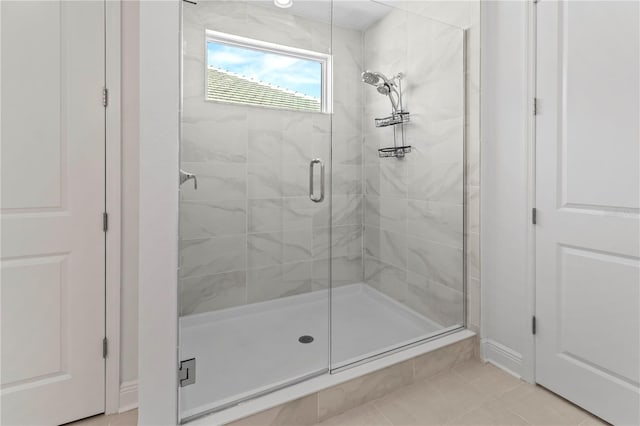 bathroom with a shower with door and tile patterned flooring