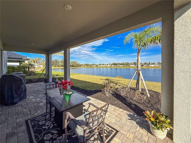 view of patio with a grill and a water view