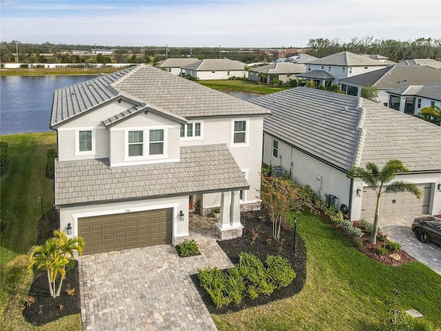 view of front facade featuring a garage, a front lawn, and a water view