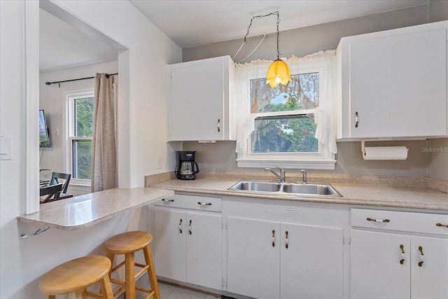 kitchen with a kitchen breakfast bar, sink, white cabinets, and decorative light fixtures